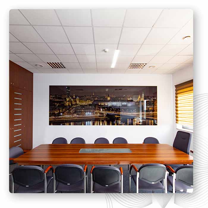 Sala konferencyjna z długim stołem, ciemnymi krzesłami i panoramiczną grafiką na ścianie