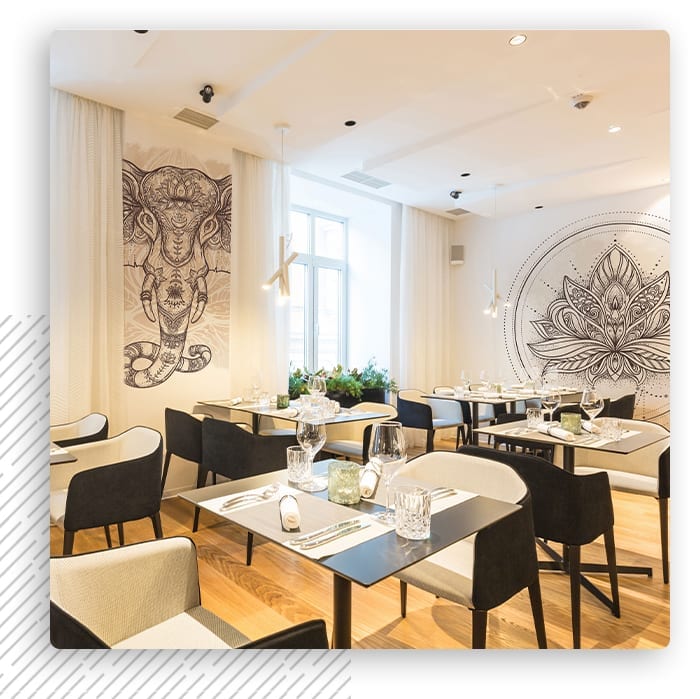 Jasna sala restauracji ze stolikami i ornamentową fototapetą na ścianach