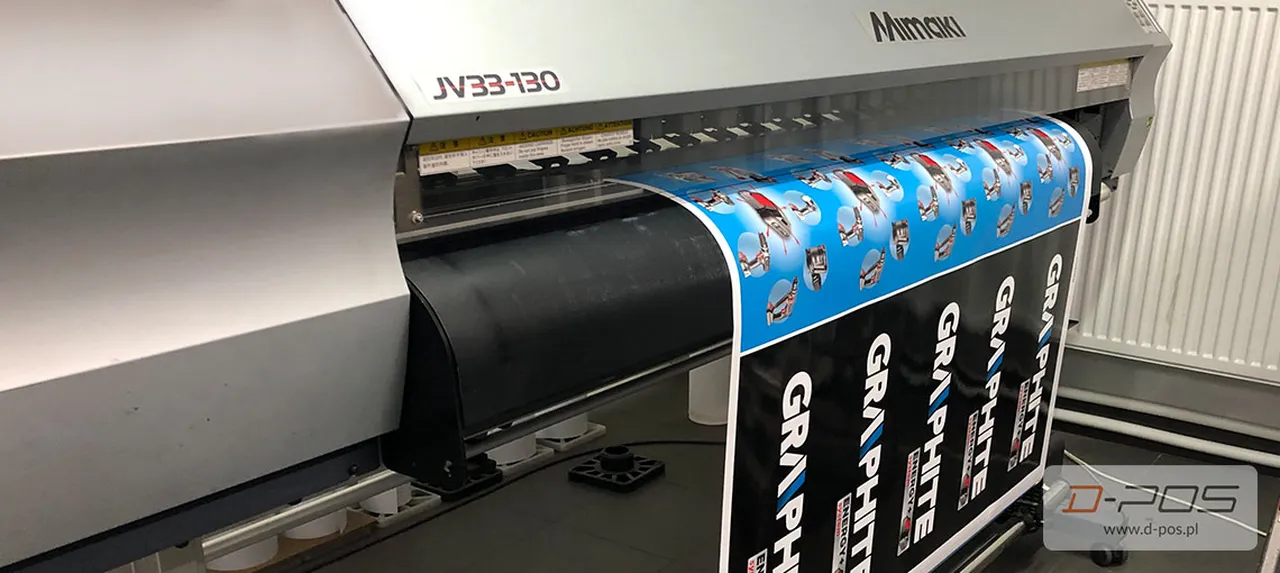 Ploter wielkoformatowy drukujący kolorową grafikę reklamową na roli materiału