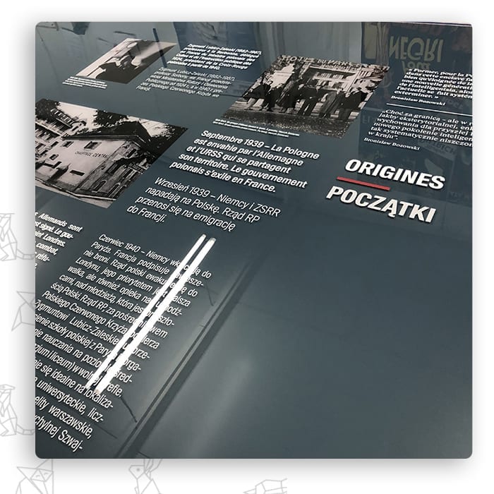 Grafitowa plansza wystawiennicza z napisem Początki i archiwalnymi zdjęciami