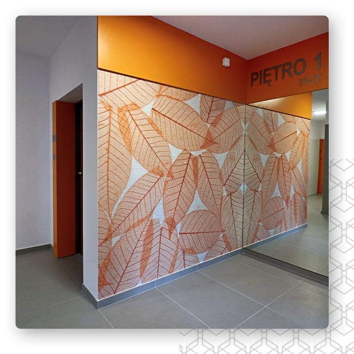 Miedziana geometryczna grafika na ścianie korytarza z pomarańczowym akcentem