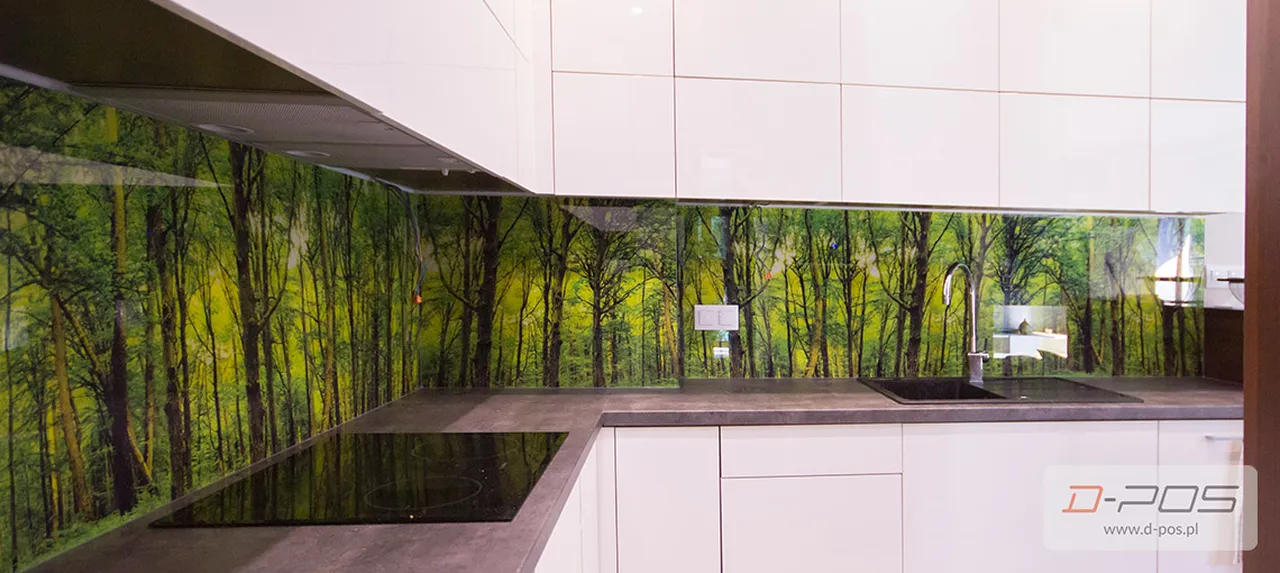 Panel szklany z fotografią zielonego lasu zamontowany między szafkami kuchennymi