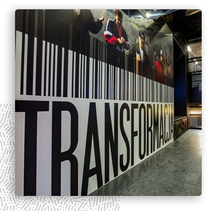 Wielkoformatowa czarno-biała grafika ścienna z napisem TRANSFORM w przestrzeni wystawienniczej